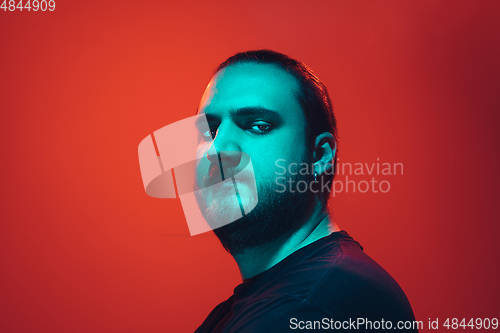 Image of Portrait of a guy with colorful neon light on red background - cyberpunk concept