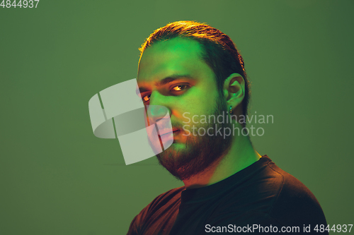 Image of Portrait of a guy with colorful neon light on green background - cyberpunk concept