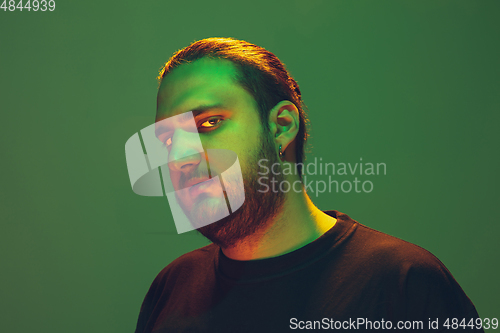 Image of Portrait of a guy with colorful neon light on green background - cyberpunk concept