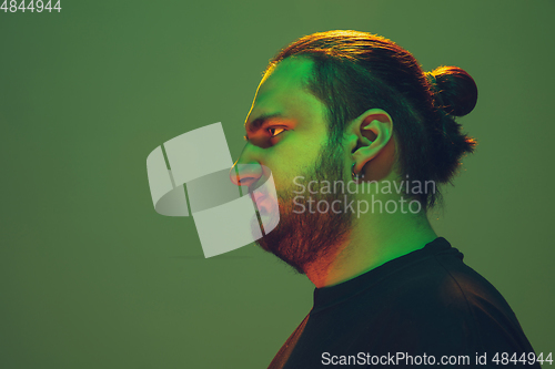 Image of Portrait of a guy with colorful neon light on green background - cyberpunk concept