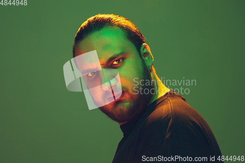 Image of Portrait of a guy with colorful neon light on green background - cyberpunk concept