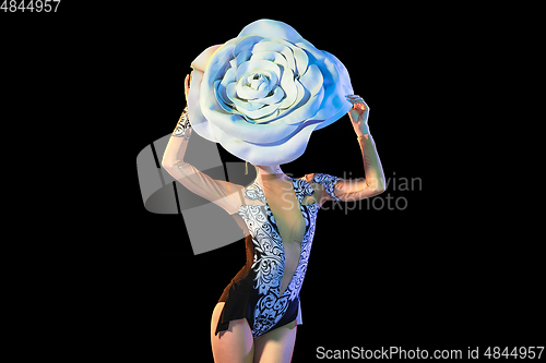 Image of Young female dancer with huge floral hat in neon light on black background