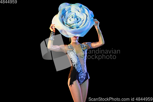 Image of Young female dancer with huge floral hat in neon light on black background