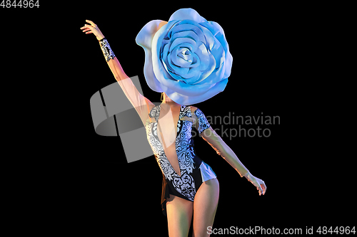 Image of Young female dancer with huge floral hat in neon light on black background