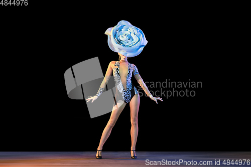 Image of Young female dancer with huge floral hat in neon light on black background