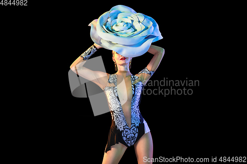 Image of Young female dancer with huge floral hat in neon light on black background