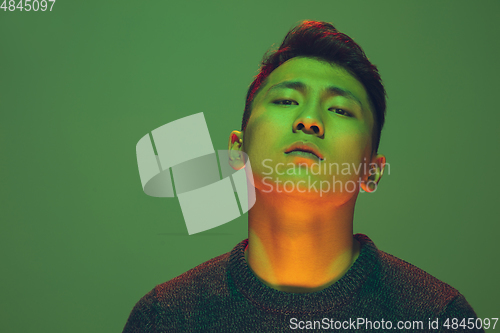 Image of Portrait of a guy with colorful neon light on green background - cyberpunk concept