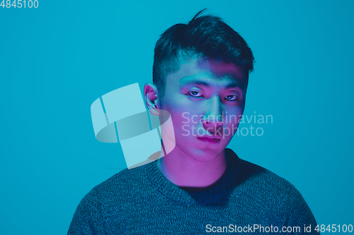 Image of Portrait of a guy with colorful neon light on blue background - cyberpunk concept