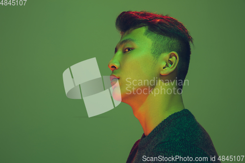 Image of Portrait of a guy with colorful neon light on green background - cyberpunk concept