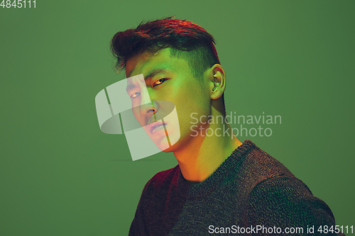 Image of Portrait of a guy with colorful neon light on green background - cyberpunk concept