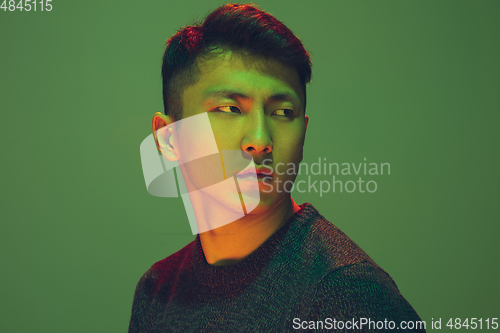 Image of Portrait of a guy with colorful neon light on green background - cyberpunk concept