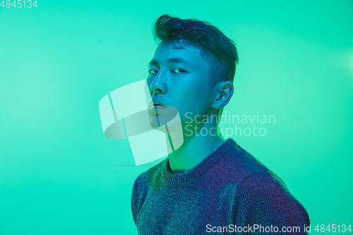 Image of Portrait of a guy with colorful neon light on green background - cyberpunk concept