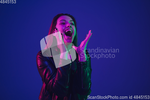 Image of Caucasian woman\'s portrait isolated on blue studio background in neon light