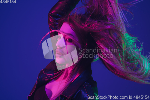 Image of Caucasian woman\'s portrait isolated on blue studio background in neon light