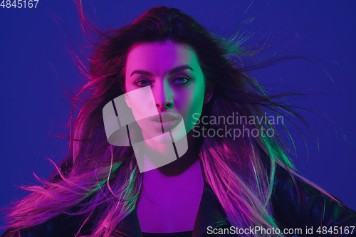 Image of Caucasian woman\'s portrait isolated on blue studio background in neon light