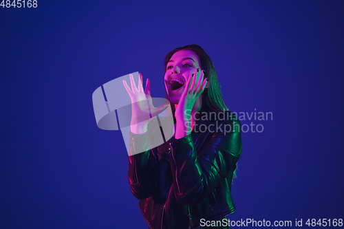 Image of Caucasian woman\'s portrait isolated on blue studio background in neon light