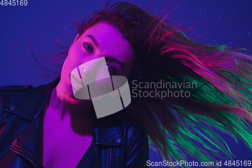 Image of Caucasian woman\'s portrait isolated on blue studio background in neon light