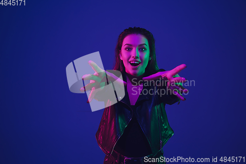 Image of Caucasian woman\'s portrait isolated on blue studio background in neon light