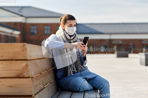 Image of woman in face mask with smartphone in city