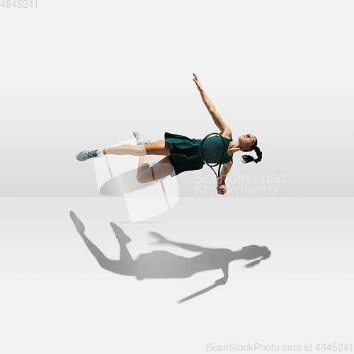 Image of Young caucasian professional sportswoman levitating, flying while playing tennis isolated on white background