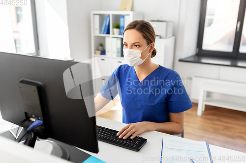 Image of doctor or nurse in mask with computer at hospital