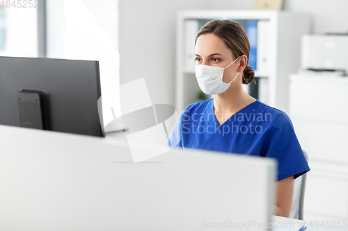 Image of doctor or nurse in mask with computer at hospital