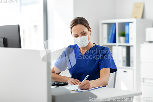 Image of doctor or nurse in mask with clipboard at hospital