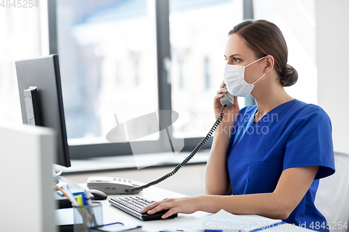 Image of doctor with computer calling on phone at hospital