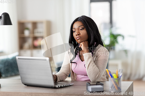 Image of bored woman with laptop working at home office