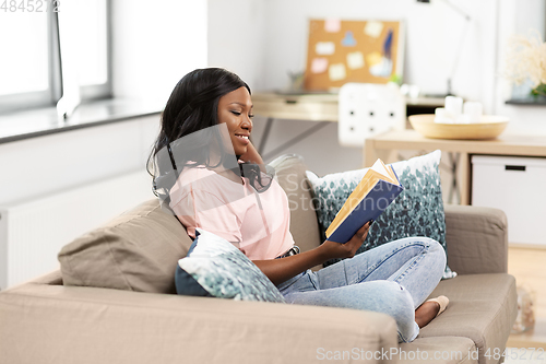 Image of happy african american woman reading book at home