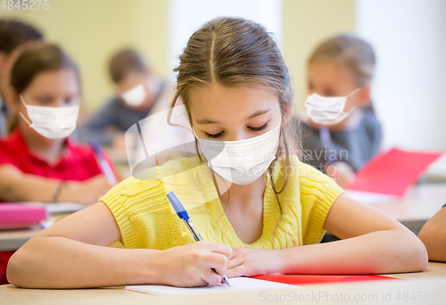 Image of group of students in masks writing test at school