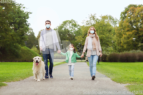 Image of family in masks with labrador dog in park