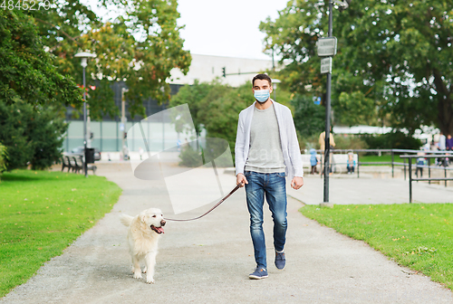 Image of man in mask with labrador dog walking in city