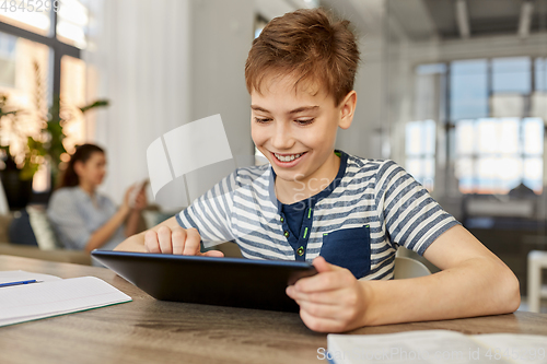 Image of student boy with tablet computer learning at home