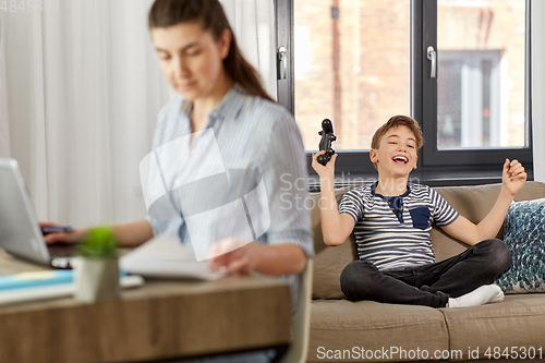 Image of happy boy with gamepad playing video game at home