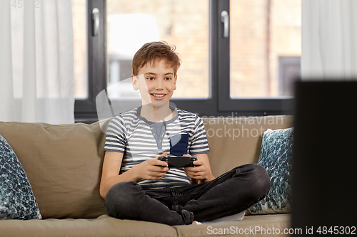 Image of boy with gamepad playing video game at home