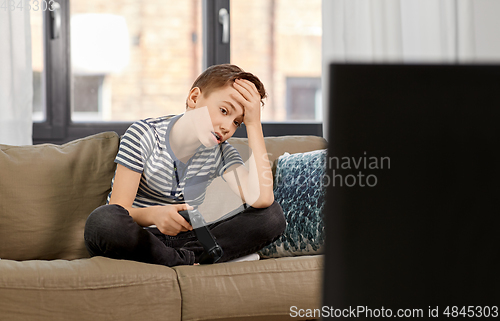 Image of sad boy with gamepad playing video game at home