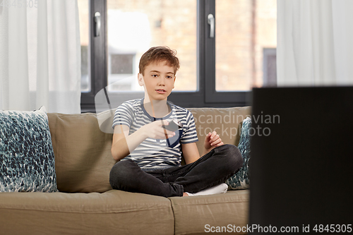 Image of boy with remote control watching tv at home