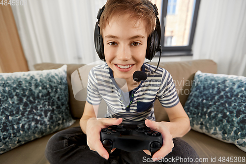 Image of boy with gamepad playing video game at home