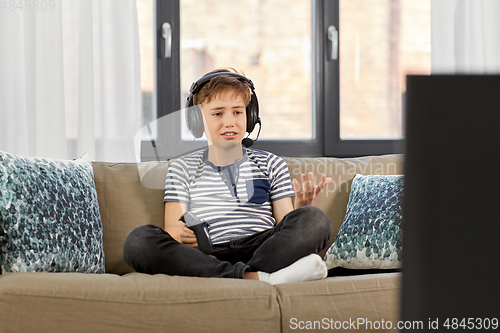 Image of upset boy with gamepad playing video game at home
