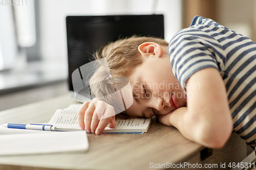 Image of tired student boy sleeping on desk at home