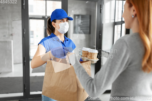 Image of delivery girl in mask giving paper bag to customer