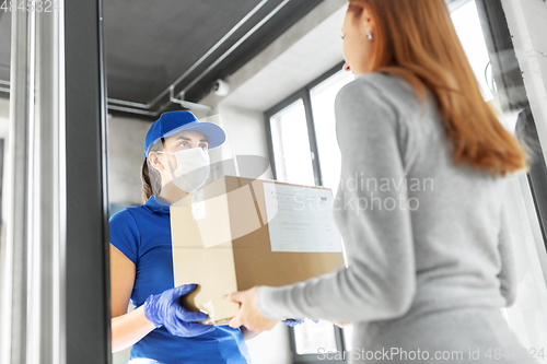 Image of delivery girl in face mask giving parcel to woman