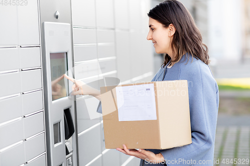 Image of smiling woman with box at automated parcel machine