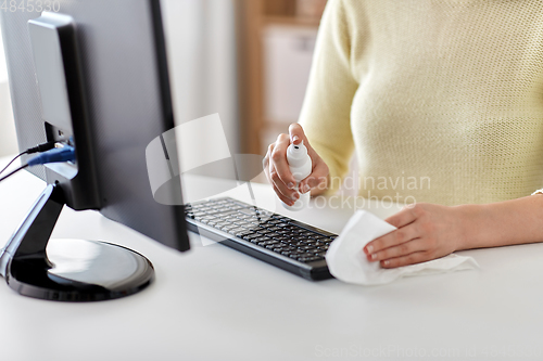 Image of close up of woman cleaning keyboard with sanitizer