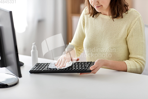 Image of close up of woman cleaning keyboard with sanitizer