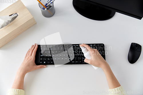 Image of close up of woman cleaning keyboard with sanitizer