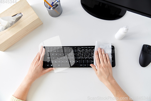 Image of close up of woman cleaning keyboard with tissue