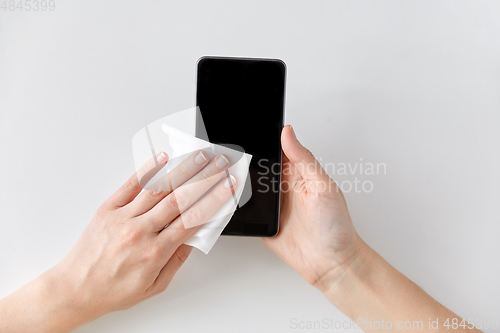 Image of close up of hands cleaning smartphone with tissue