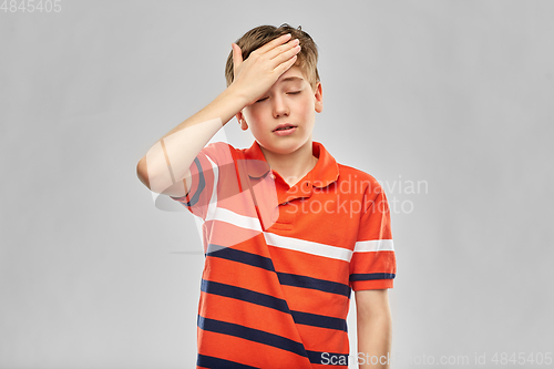 Image of boy in red polo t-shirt having headache